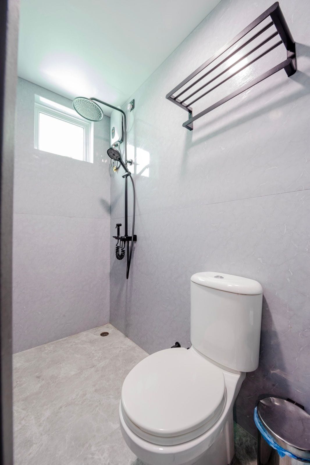 Un baño pequeño con inodoro, ducha y un perchero para toallas.