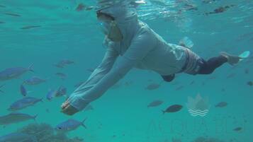 Una persona nadando bajo el agua rodeada de peces.