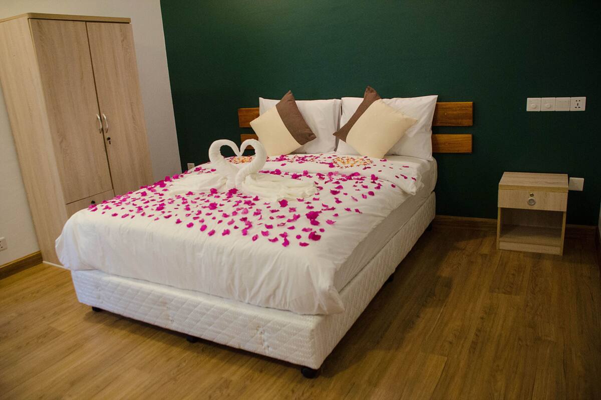 A neatly made bed with a white comforter, two pillows, and a decorative swan made of fabric.