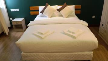 A neatly made bed with white bedding and two pillows, a wooden headboard, a small bedside table, and a nightstand.