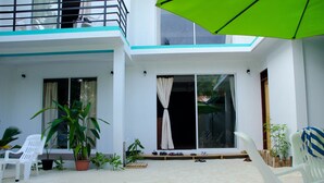 A two-story building with a balcony, potted plants, and outdoor seating.