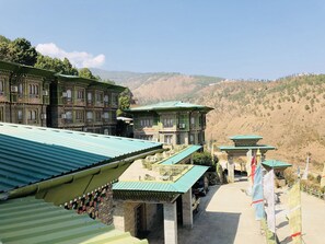 A traditional building with multiple levels and balconies, a paved pathway, and flags.