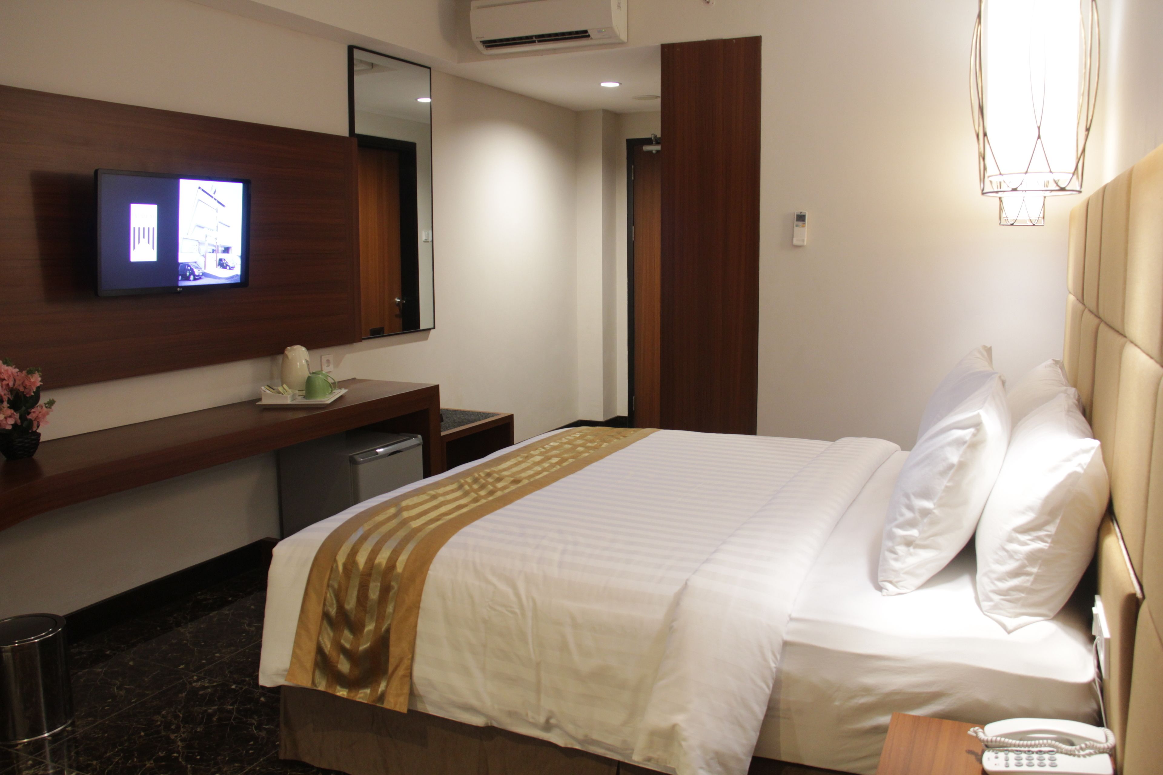 Een hotelkamer met een bed, nachtkastje, televisie en een spiegel.