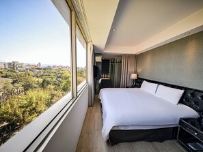 A modern hotel room with a large bed, a TV, a bathroom, and a city view. - CHECK inn Taipei Main Station (Taipei)