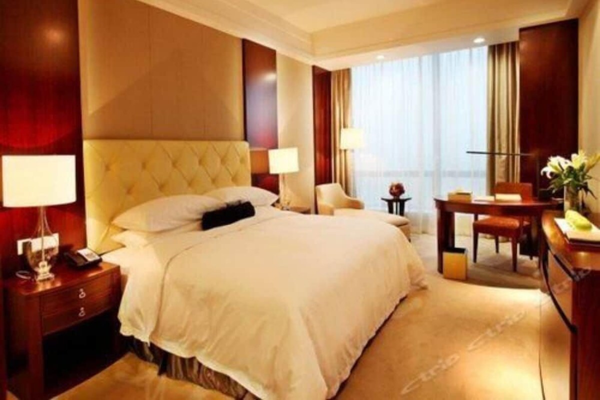 Una habitación de hotel con una cama grande, mesitas de noche, un escritorio y una silla.