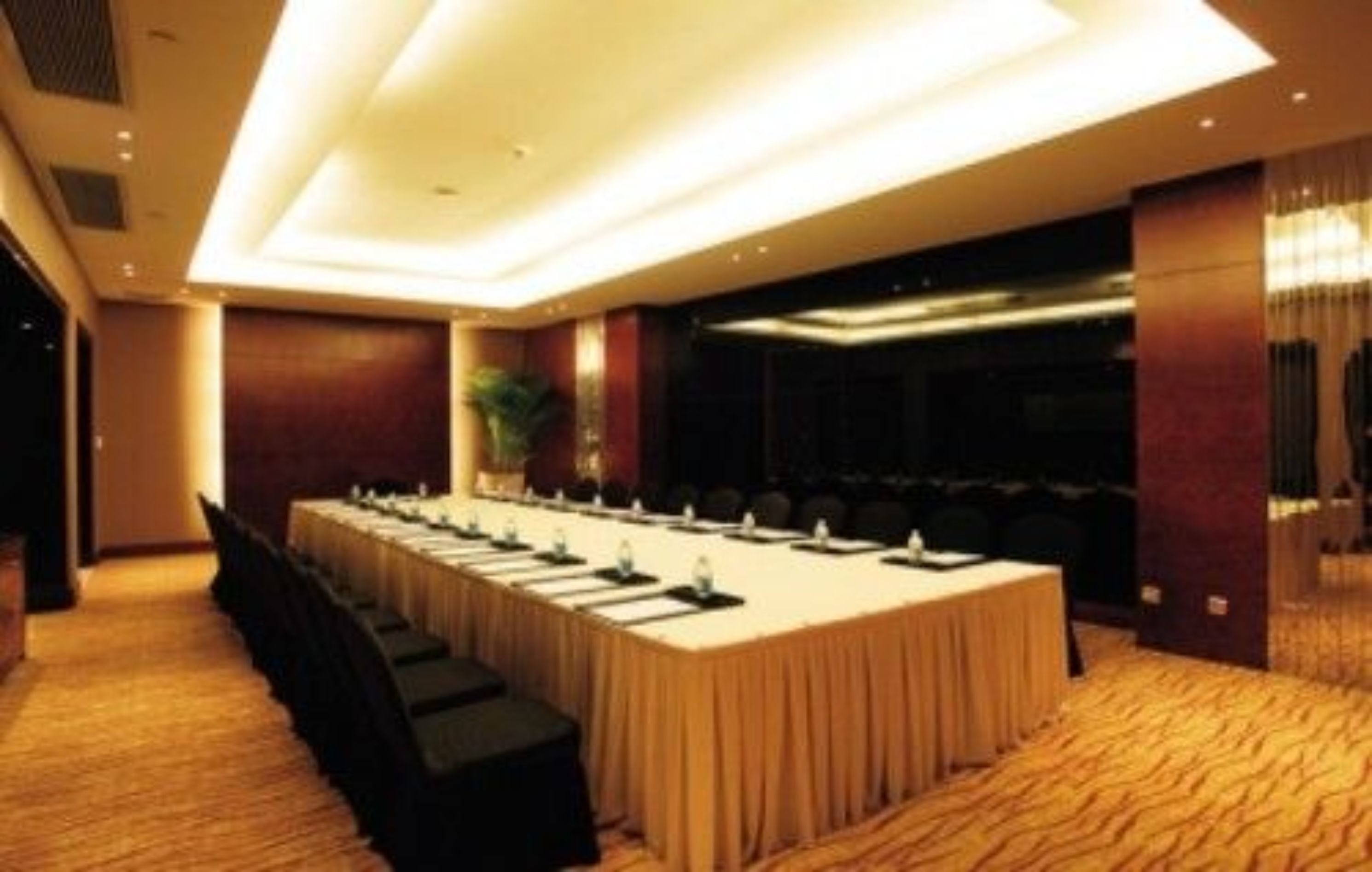 A conference room with a long table, chairs, and a carpeted floor.