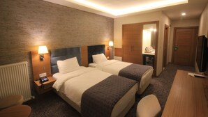 A hotel room with two beds, a desk, a chair, a TV, and a bathroom. - Garden Zara Hotel (Zara)