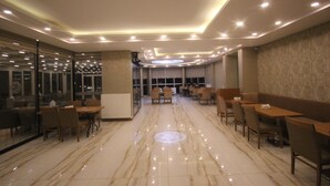 A spacious restaurant with a polished marble floor, multiple seating areas, and a modern ceiling design with recessed lighting. - Garden Zara Hotel (Zara)