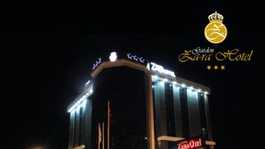 A hotel with a prominent 'Garden Zara Hotel' sign, a 'Cafe & Restaurant' sign, and a 'ZARA HOTEL' sign. - Garden Zara Hotel (Zara)