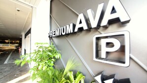 En bygningseingang med et skilt der siger "PREMIUM AVA" og et parkeringssymbol.