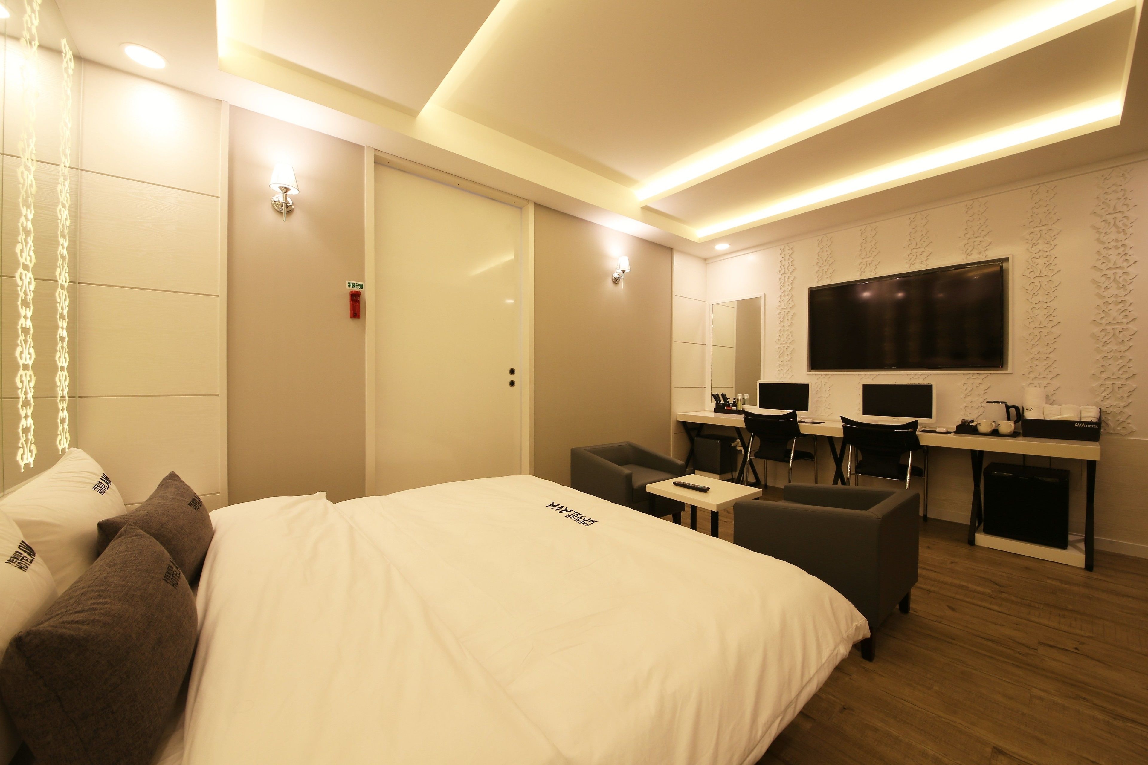 A hotel room with a bed, a desk with two chairs, a TV, and a small table.