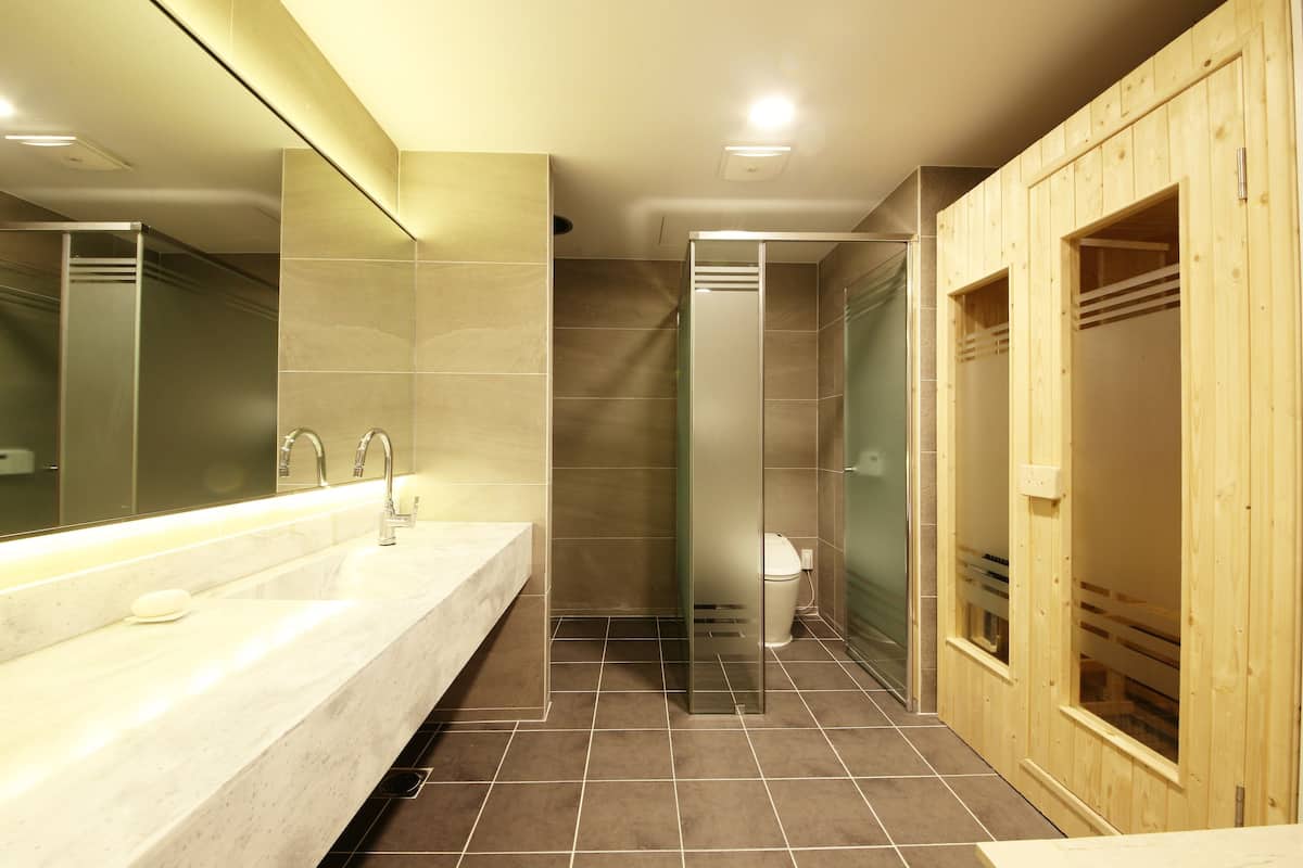 Un baño moderno con un espejo grande, un lavamanos, ducha y vestidores de madera.