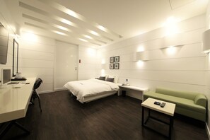 A modern hotel room with a bed, desk, green sofa, and a small table with a remote control. - Premium AVA Hotel Sasang (Busan)