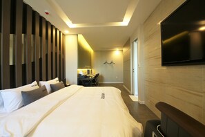 A modern hotel room with a large bed, a desk, and a flat-screen TV mounted on the wall. - Premium AVA Hotel Sasang (Busan)