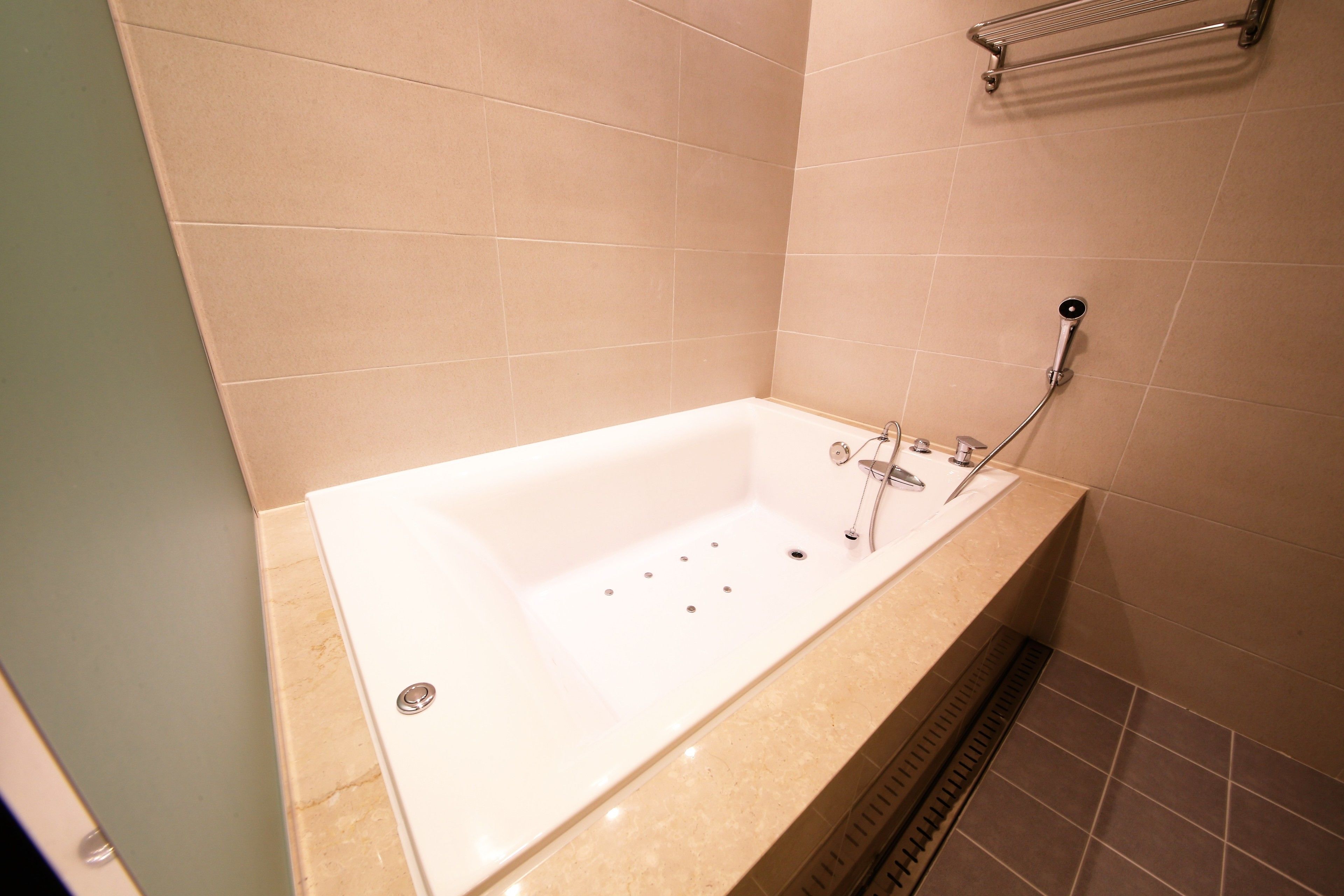 A modern bathroom with a freestanding bathtub, a showerhead, and a towel rack.