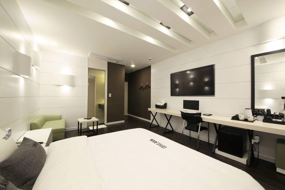 Una habitación de hotel moderna con una cama grande, un escritorio, una silla y un espejo.