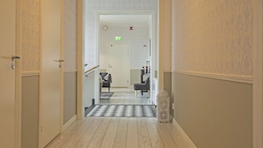 A hallway with wooden flooring, a checkered rug, and a white decorative lantern. - Norrfly Herrgård AB (Kilafors)
