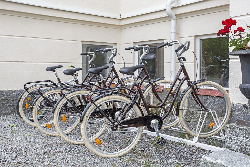A row of bicycles parked outside a building with a white exterior and a window.