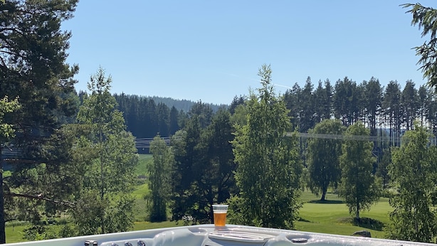 A hot tub with a clear view of a golf course and forest in the background. - Norrfly Herrgård AB (Kilafors)