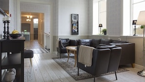 A modern living room with a leather sofa, a small table, and a decorative clock on the wall. - Norrfly Herrgård AB (Kilafors)