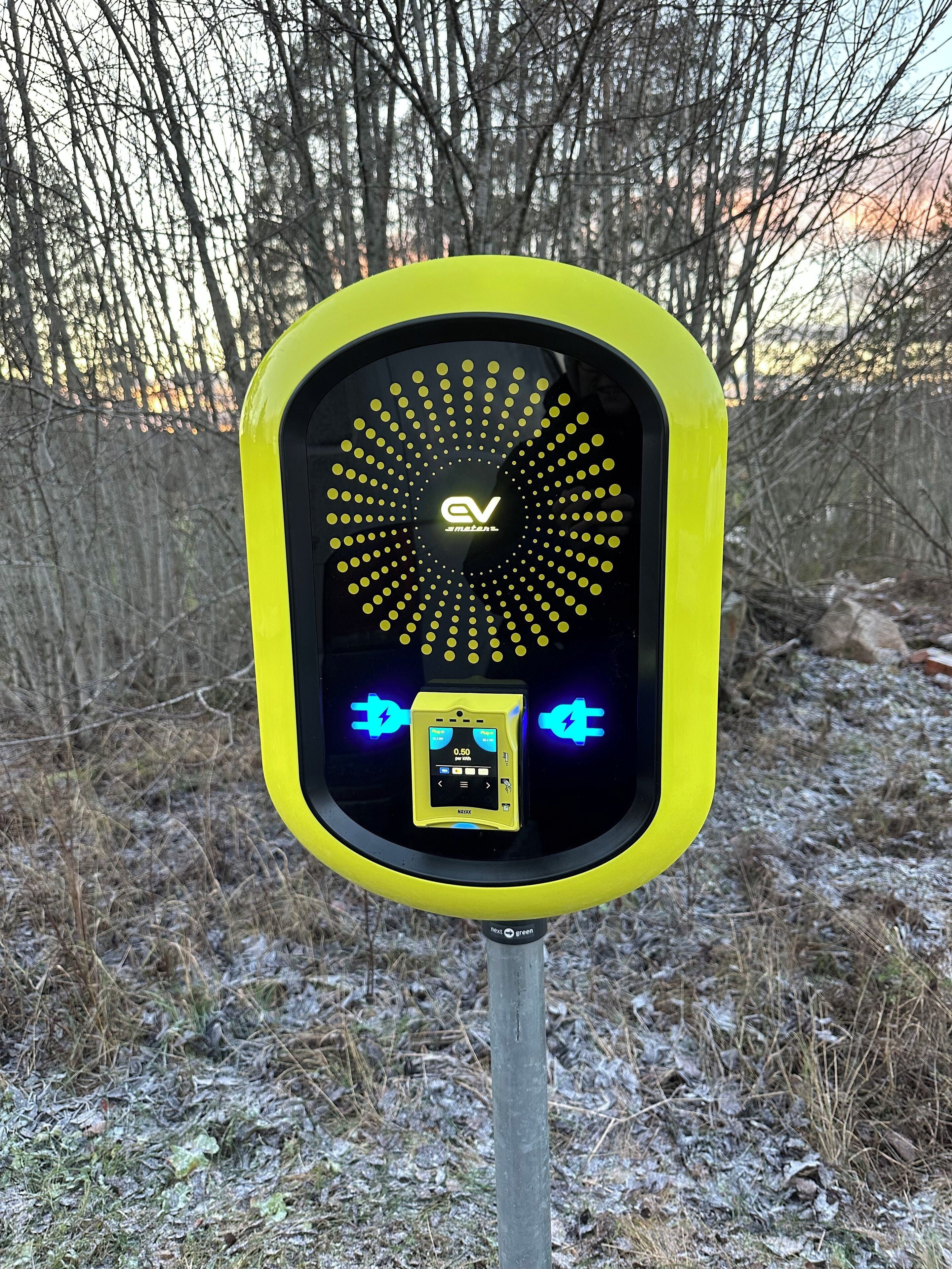 A yellow and black electric vehicle charging station with a digital display and charging symbols.