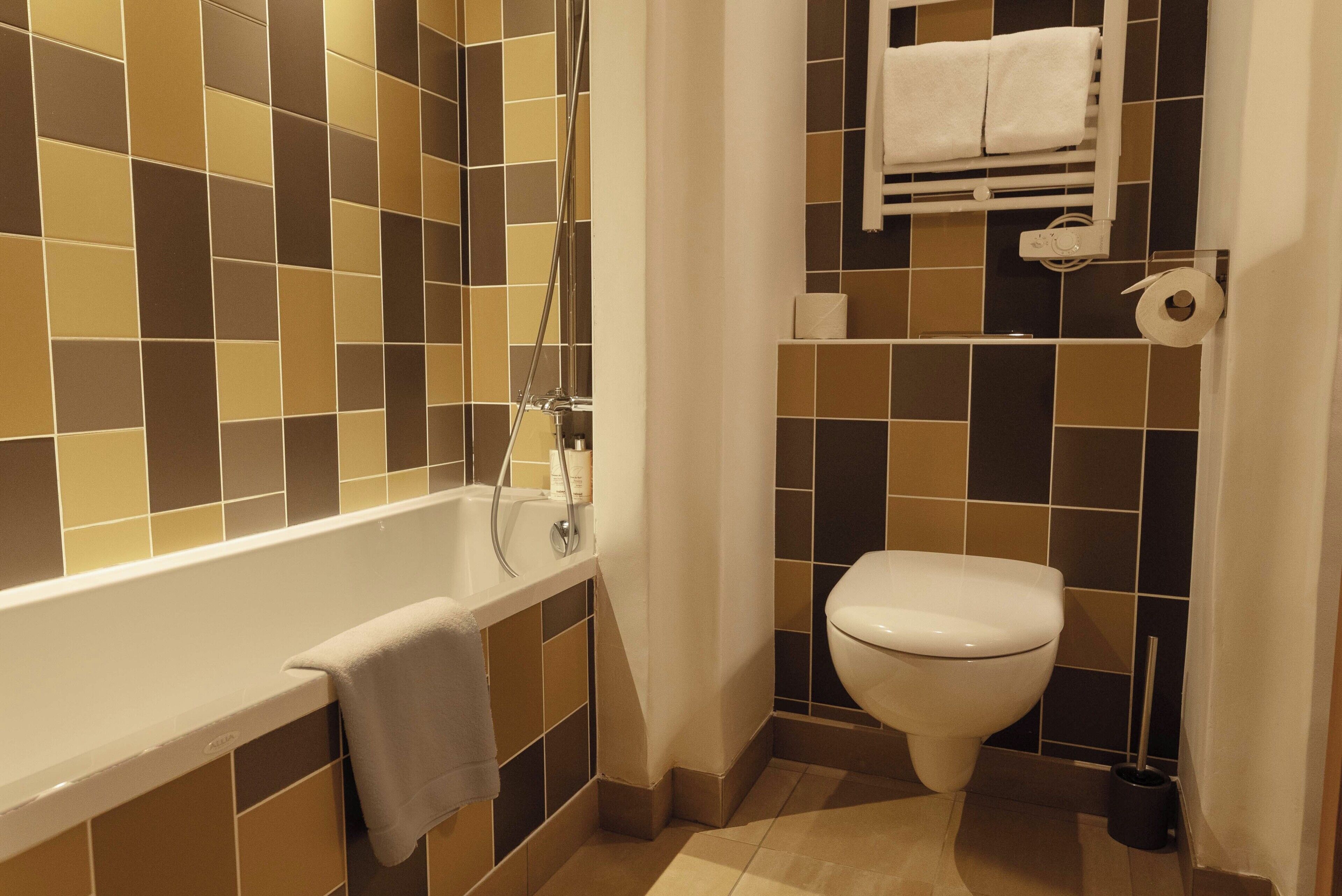 Kylpyhuone, jossa on kylpyamme, wc ja laatoitetut seinät.