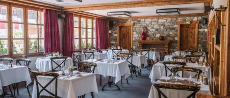 Un restaurante con varias mesas y sillas, una pared de piedra y una chimenea.