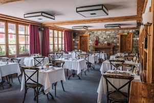 A restaurant with multiple tables and chairs, a stone wall, and a fireplace.