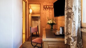 Un intérieur en bois avec une chaise, une table ornée d’un vase de fleurs et un téléviseur à écran plat fixé au mur.