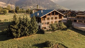 Un chalet à deux étages doté d’un balcon, niché au cœur d’un paysage montagneux.