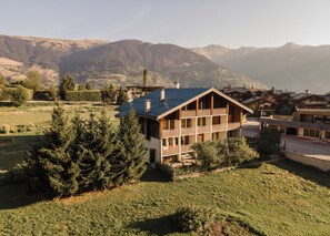 Een chalet met twee verdiepingen en een balkon, gelegen in een bergachtig landschap.