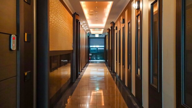 A hotel corridor with a reflective floor, recessed lighting, and doors on both sides. - Charlot Castle Hotel (Pyeongtaek)
