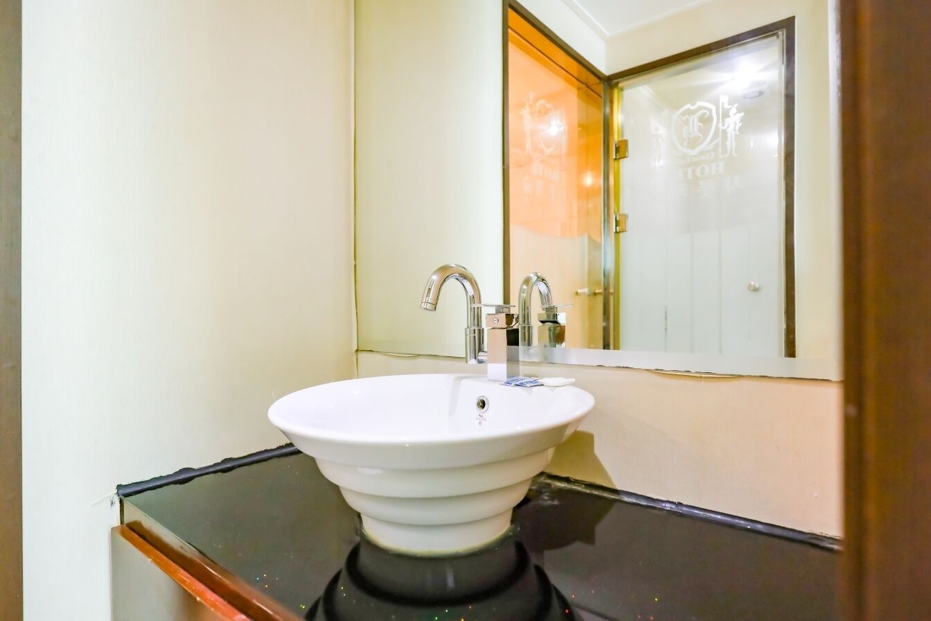 A bathroom with a white sink, two faucets, and a mirror.