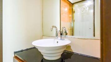A bathroom with a white sink, two faucets, and a mirror.