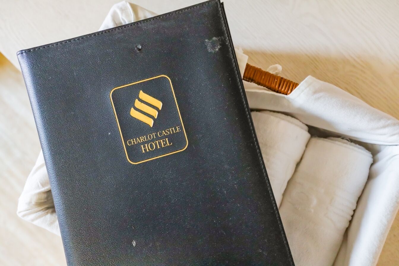 Ein gebundenes, schwarzes Buch mit dem Schriftzug "CHARLOT C CASTLE HOTEL" und einem Logo.