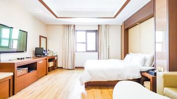 Una habitación de hotel con una cama, un escritorio con ordenador, una televisión y una ventana con cortinas.