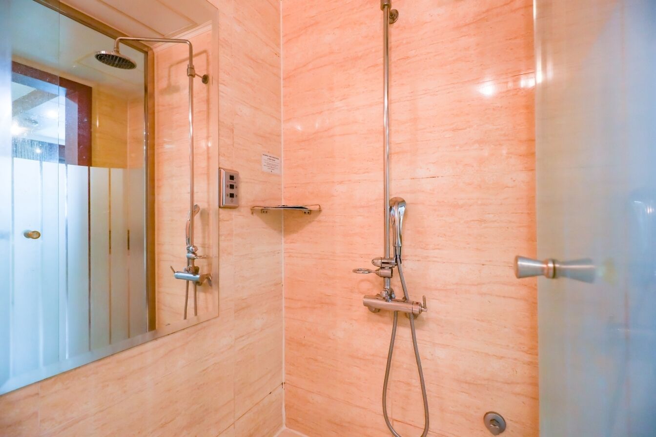 Un baño con cabina de ducha de vidrio, ducha de mano, grifo empotrado en la pared y un perchero para toallas.