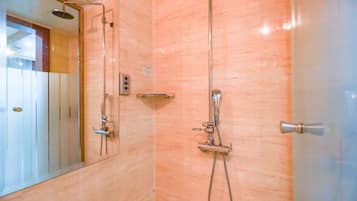 Un baño con cabina de ducha de vidrio, ducha de mano, grifo empotrado en la pared y un perchero para toallas.
