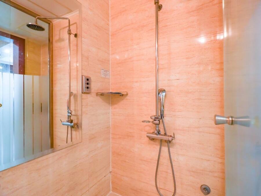 Un baño con cabina de ducha de vidrio, ducha de mano, grifo empotrado en la pared y un perchero para toallas.