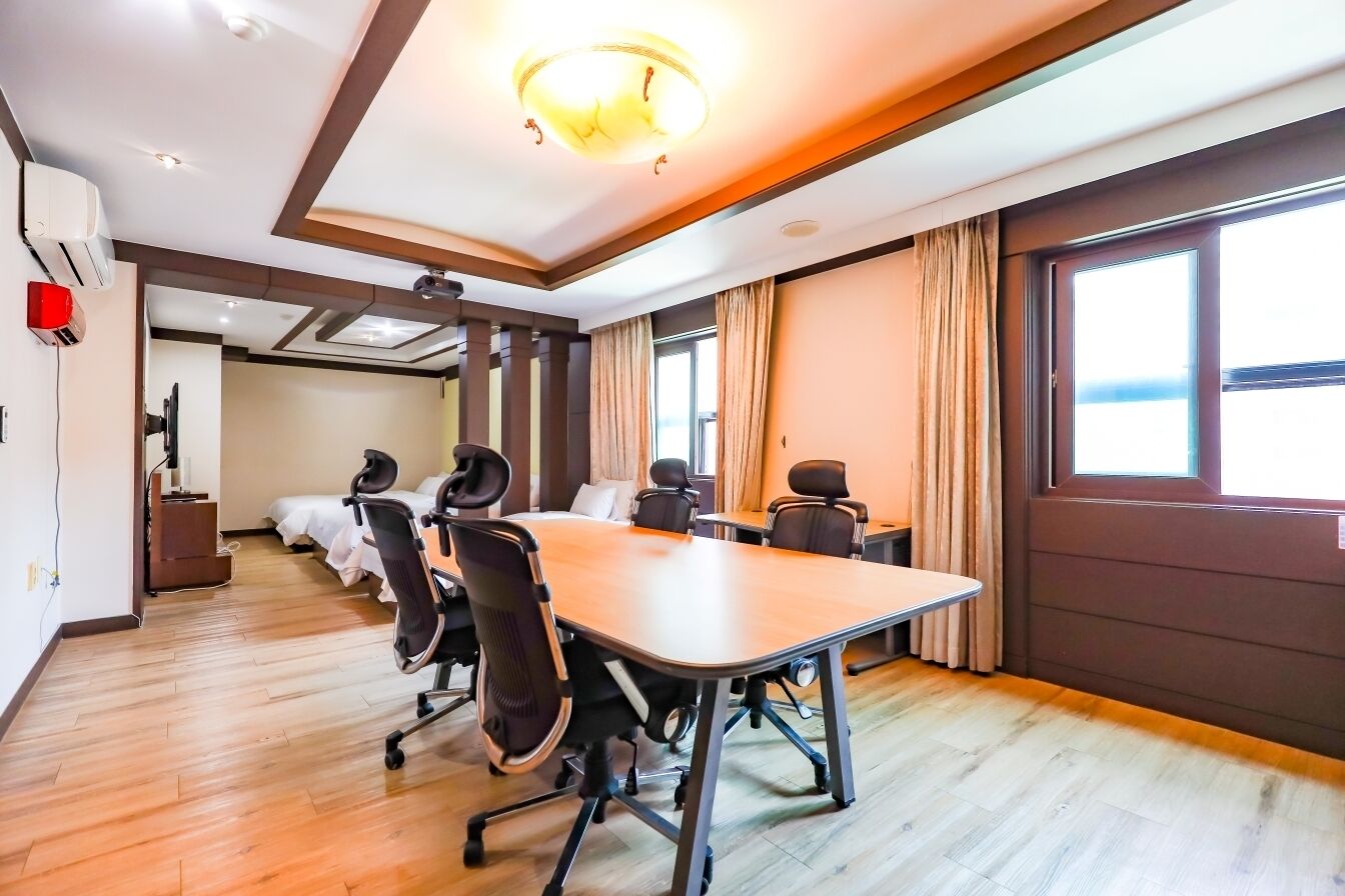 A conference room with a long table, several chairs, and a ceiling light fixture.