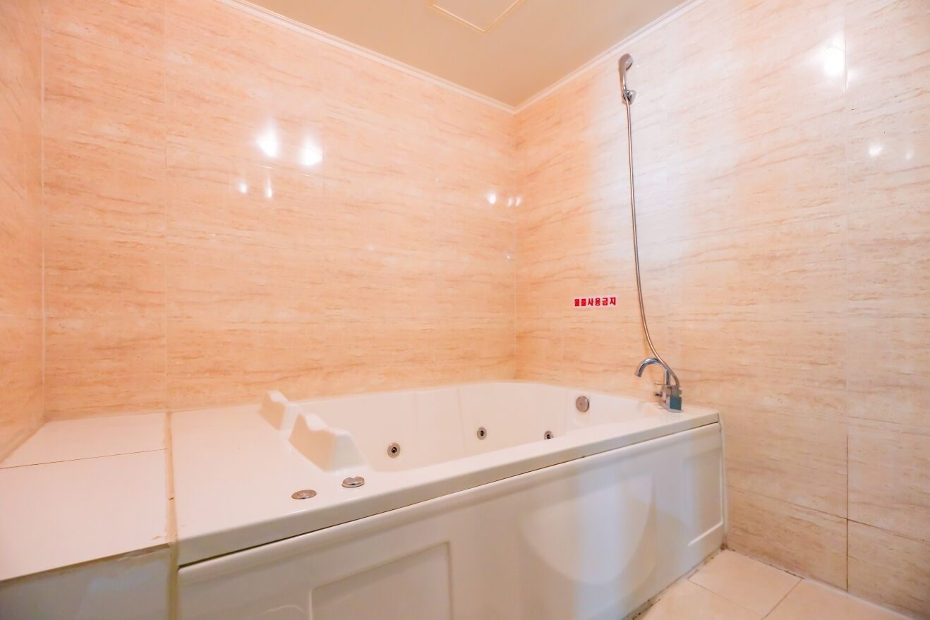 A modern bathroom with a freestanding bathtub, a showerhead, and a tiled wall.