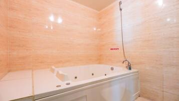 A modern bathroom with a freestanding bathtub, a showerhead, and a tiled wall.