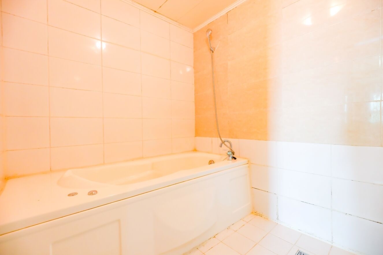 A bathroom with a bathtub, white tiled walls, and a shower area.