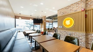 A restaurant with a brick wall, wooden tables, and leather booths. - Paulownia Hostel & Guest House (Yeosu)