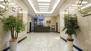 A hotel lobby with a reception desk, large mirrors, and potted plants. - Geosung Hotel (Eumseong)