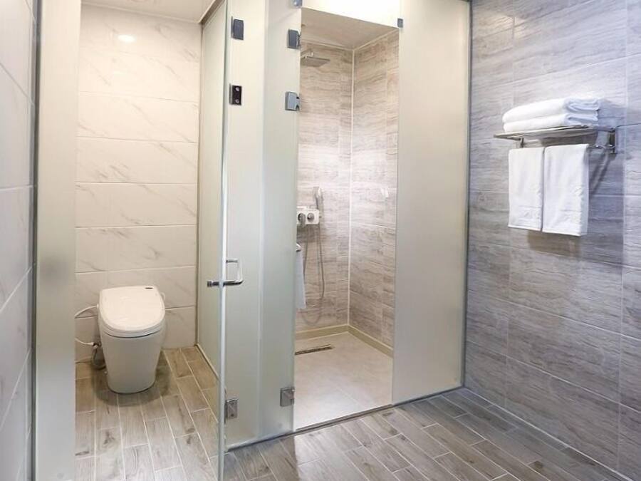 A modern bathroom with a glass shower enclosure, a toilet, and a towel rack.