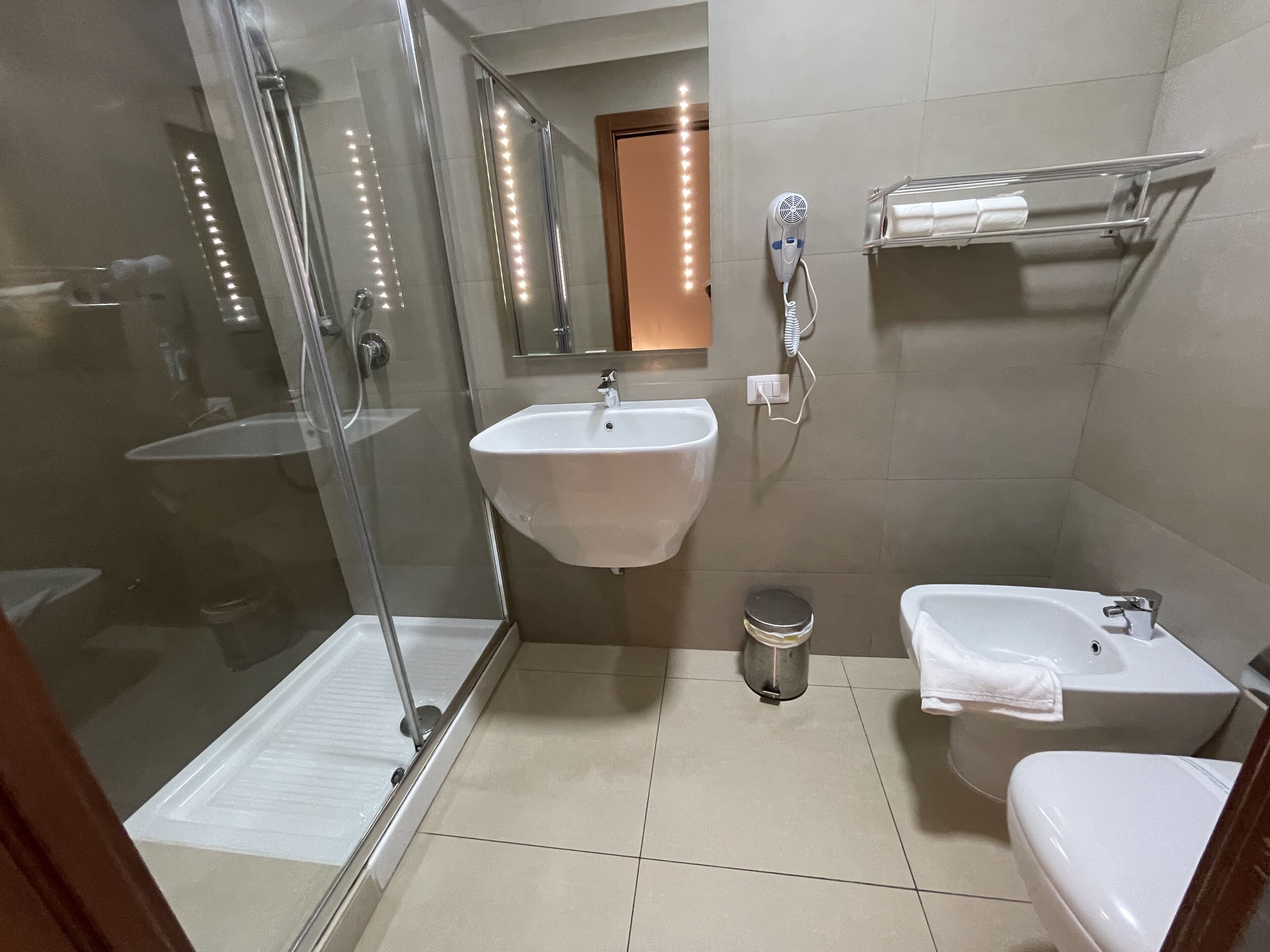 Un baño con ducha de vidrio, lavabo, bidé y retrete.