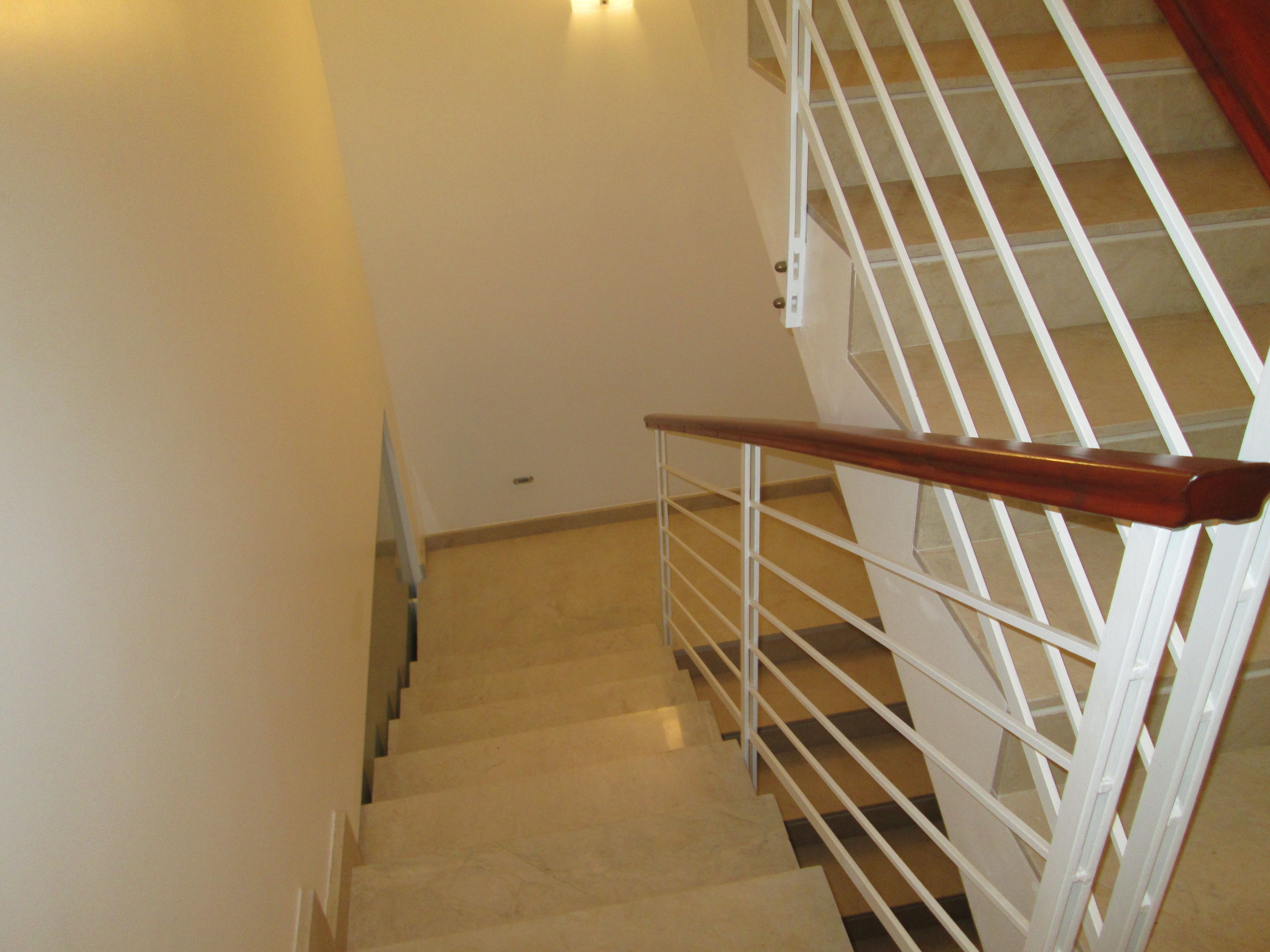 A staircase with a wooden handrail and white metal railings.