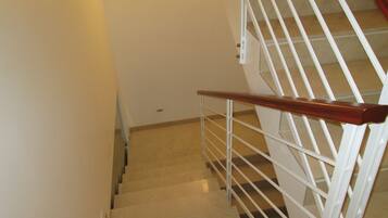 A staircase with a wooden handrail and white metal railings.