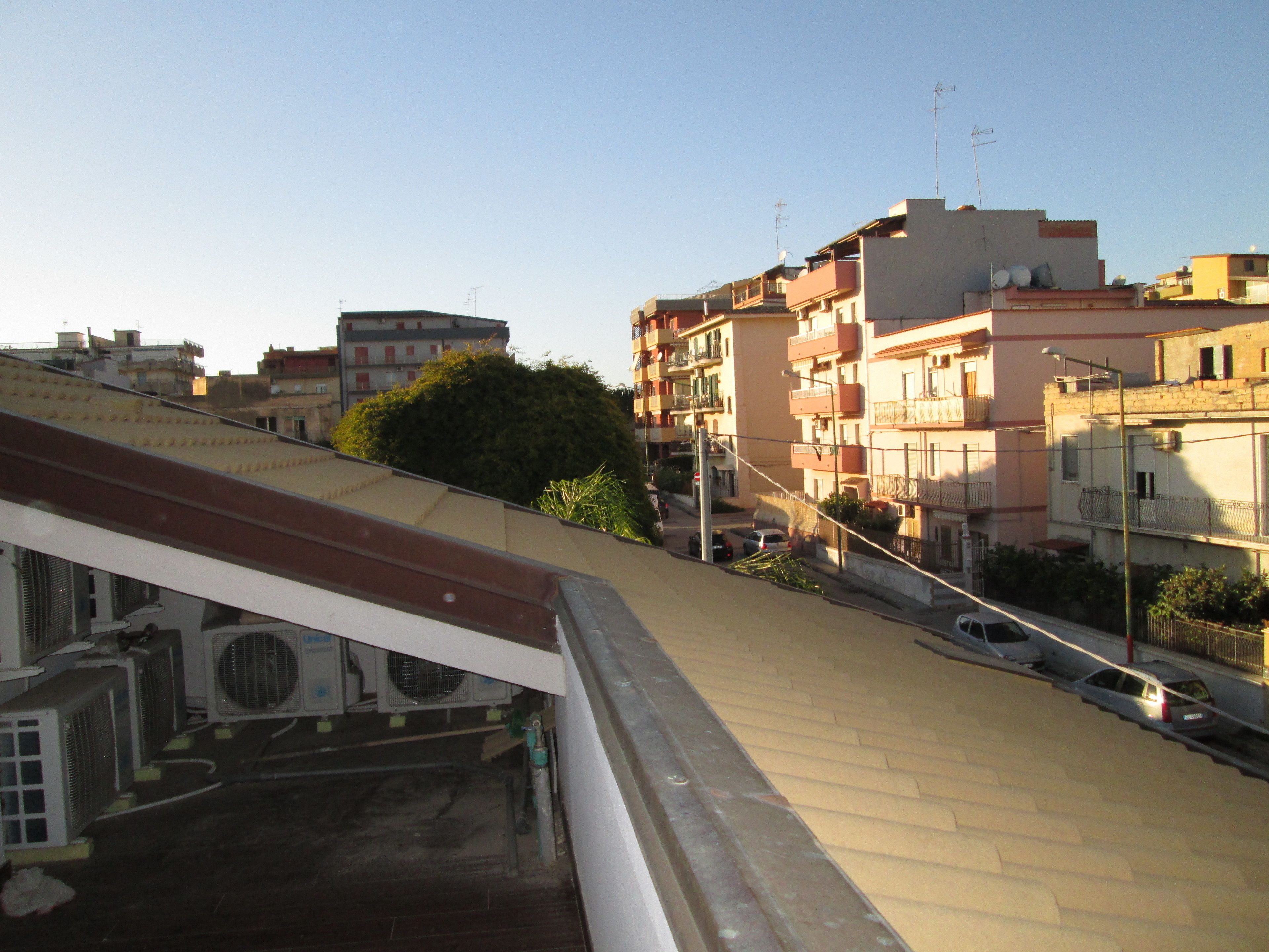 A residential area with multi-story buildings, a visible street, and a clear sky.